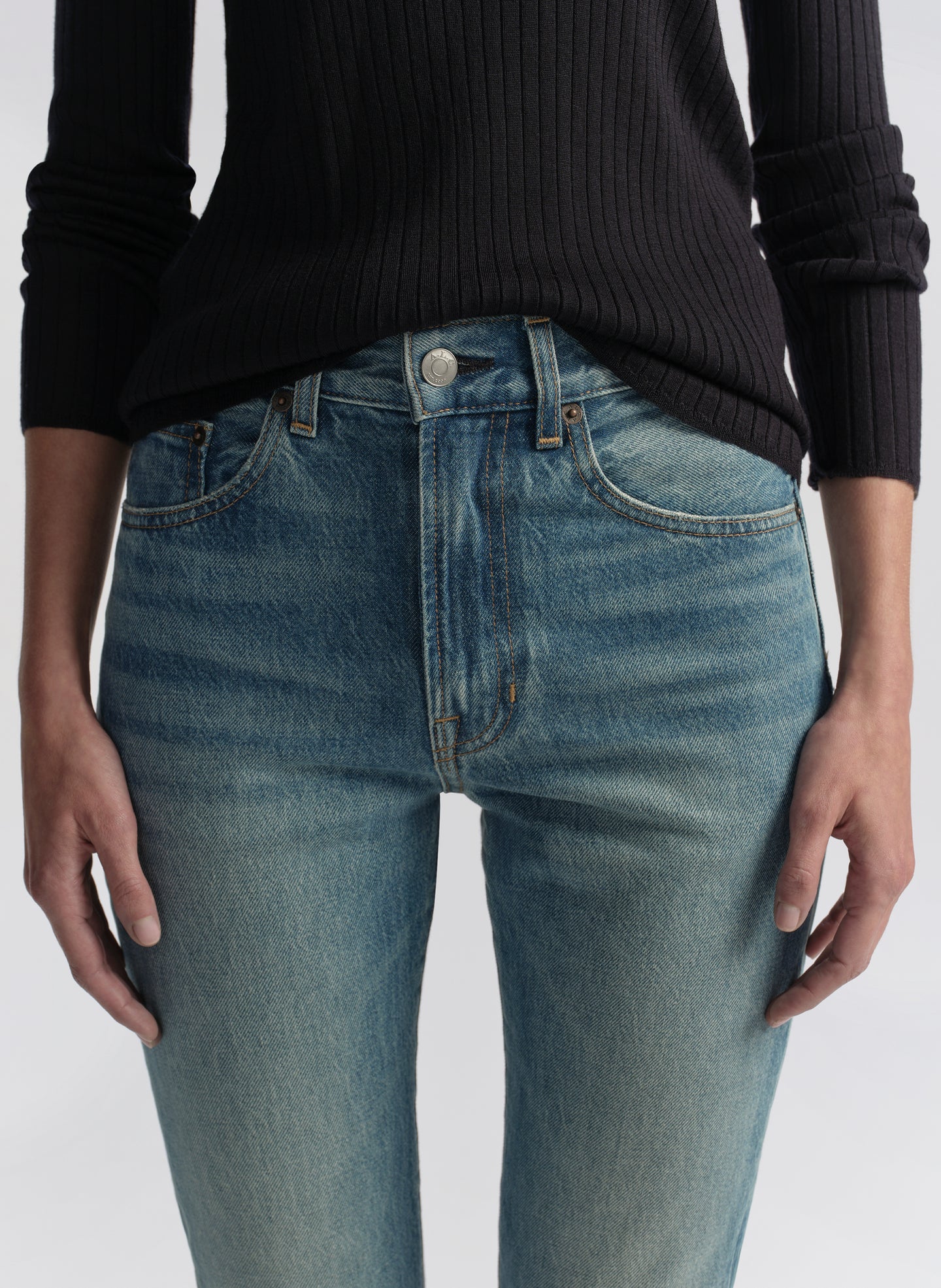 Woman wearing a navy blue shirt and blue jeans on a white background