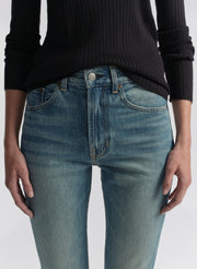 Woman wearing a navy blue shirt and blue jeans on a white background