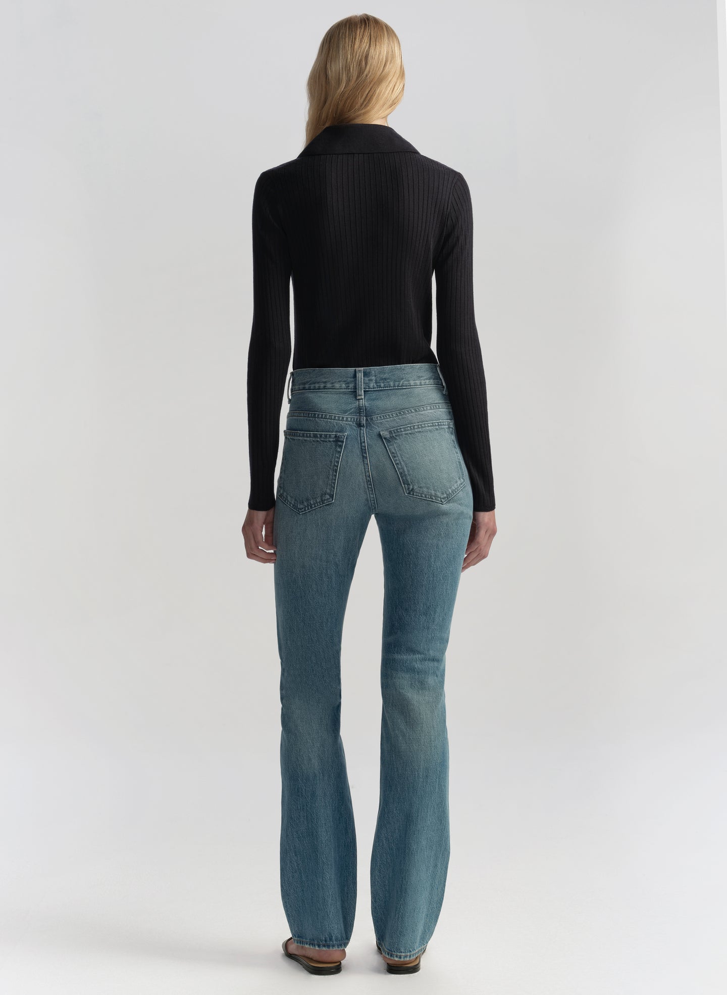 Woman wearing a navy blue shirt and blue jeans on a white background