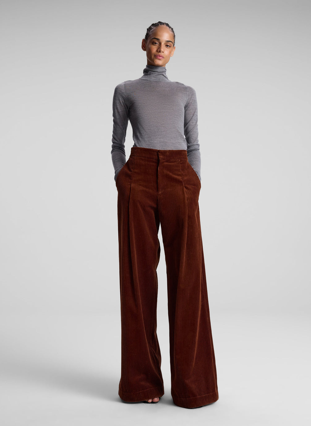 woman wearing grey turtleneck and maroon corduroy pants