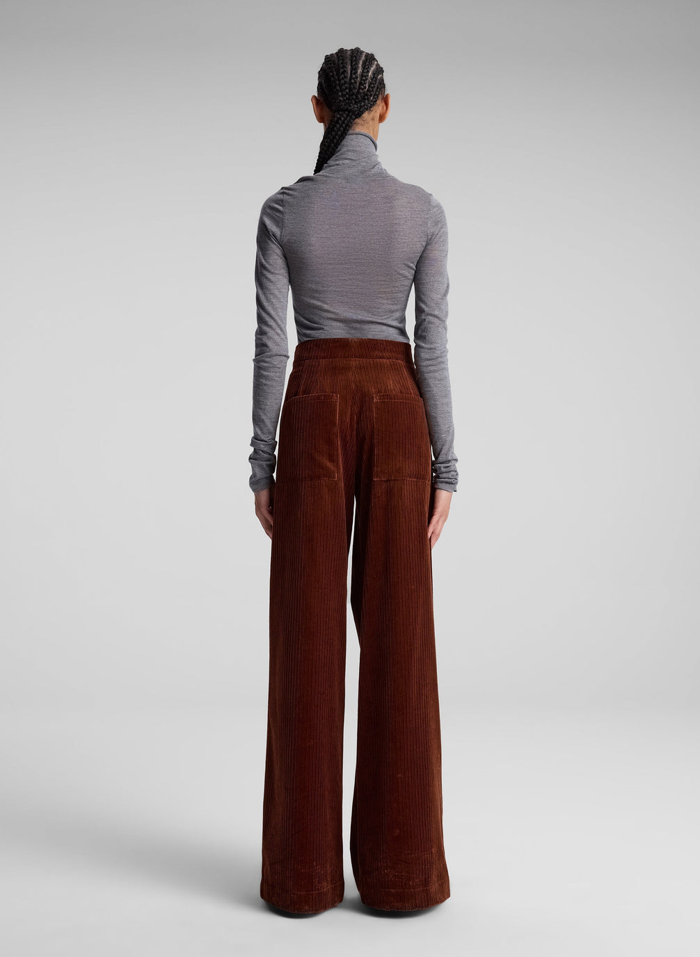 woman wearing grey turtleneck and maroon corduroy pants