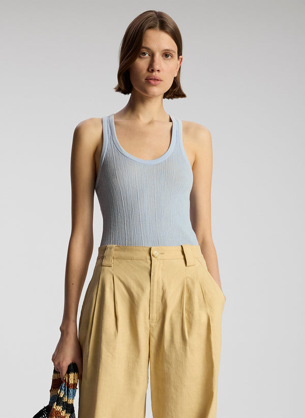 front view of woman wearing light blue tank top and tan pants