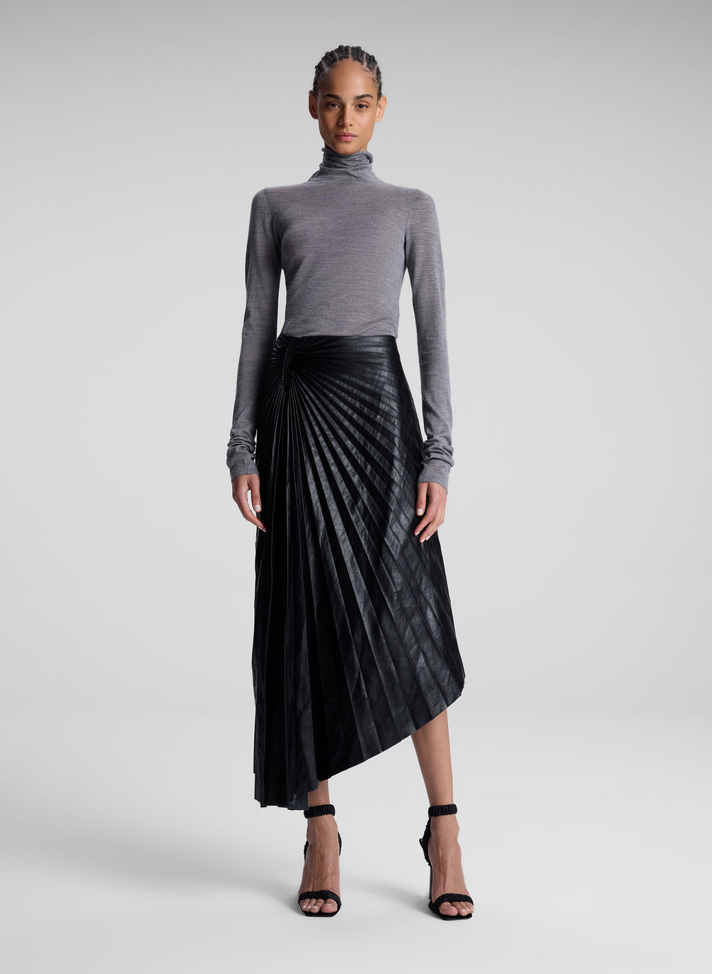 woman wearing grey turtleneck and black vegan leather pleated skirt