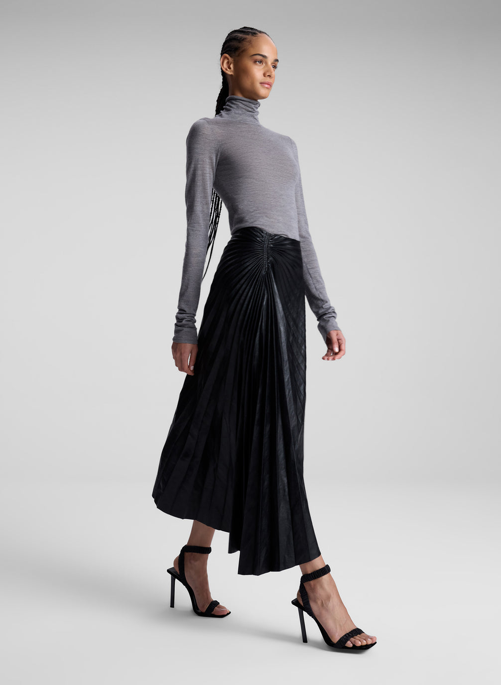 woman wearing grey turtleneck and black vegan leather pleated skirt