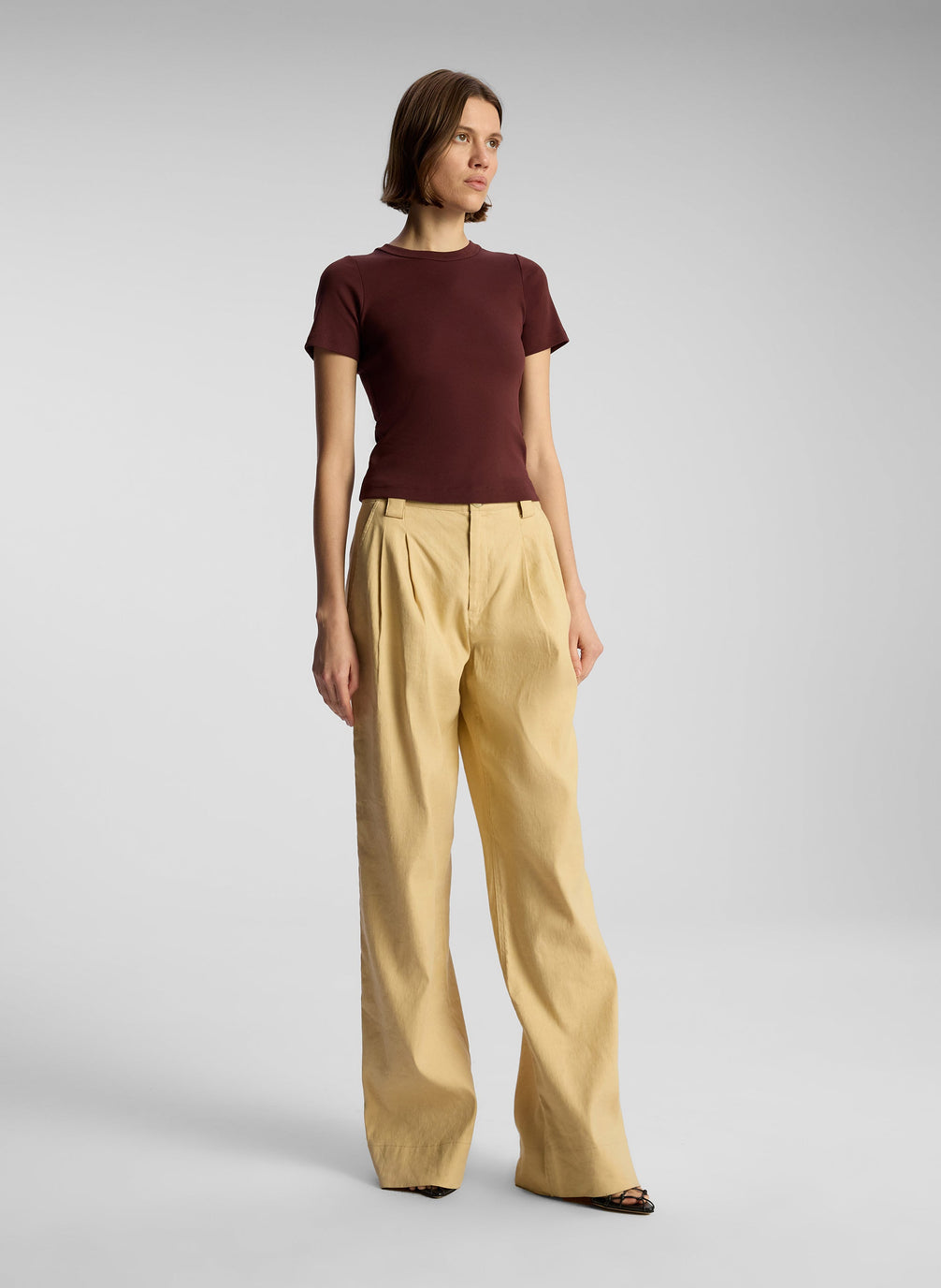 side view of woman wearing brown t shirt and tan pants