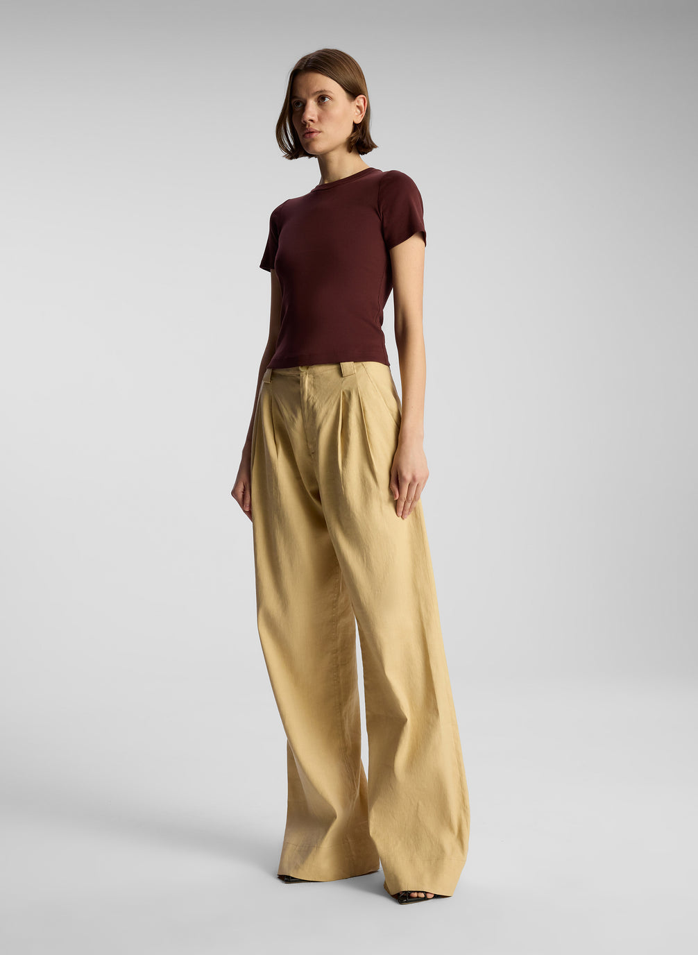 side view of woman wearing brown t shirt and tan pants