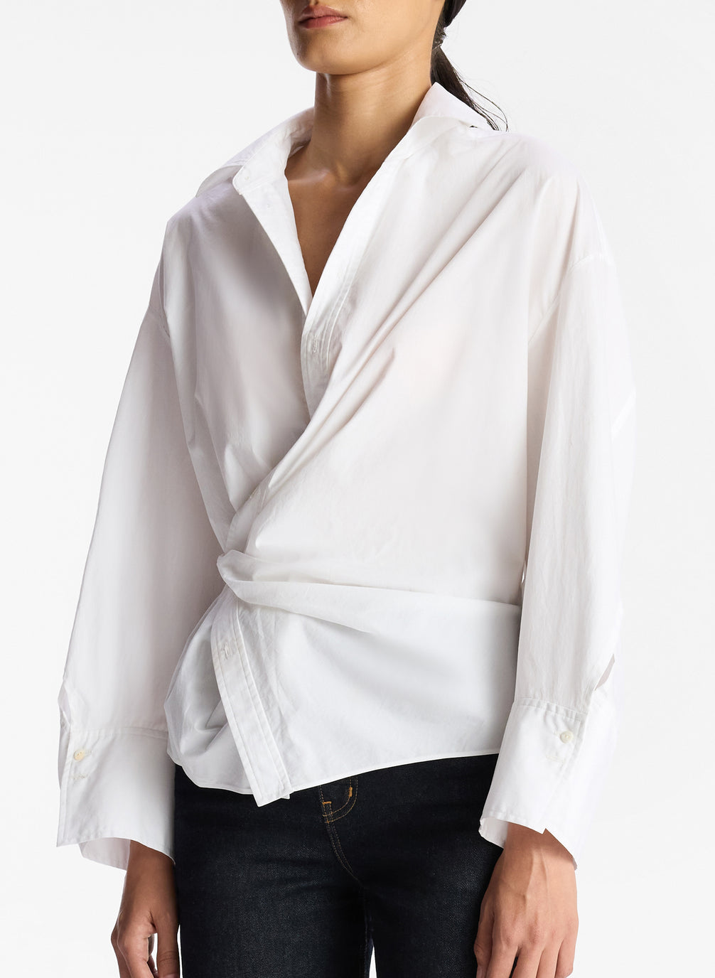 detail view of woman wearing white collared cotton wrap top and dark wash denim jeans