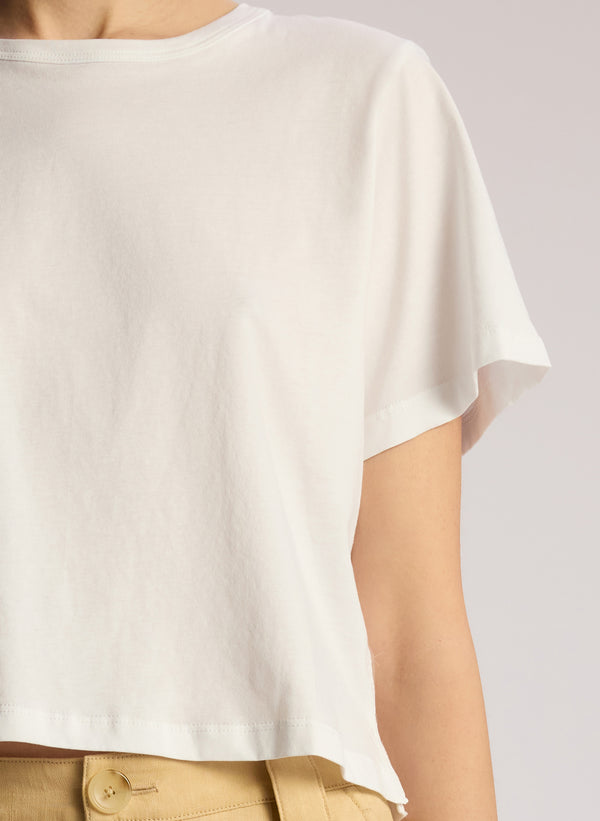 detail view of woman wearing white short sleeve tshirt and tan pants