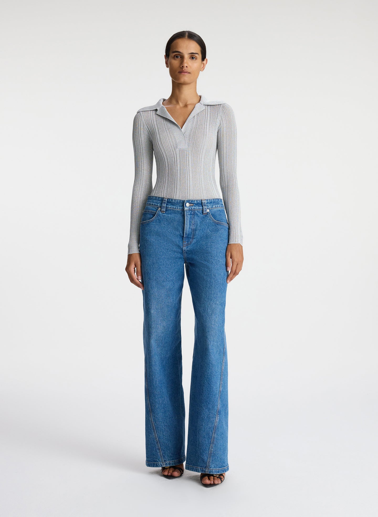 front view of woman in silver long sleeve top and medium blue wash jeans