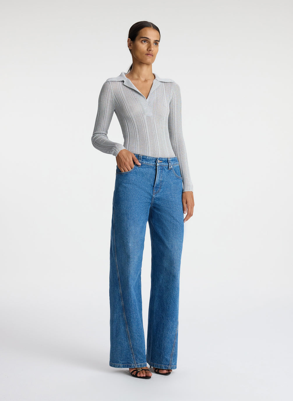 front view of woman in silver long sleeve top and medium blue wash jeans