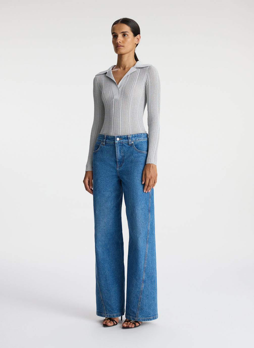 side view of woman in silver long sleeve top and medium blue wash jeans