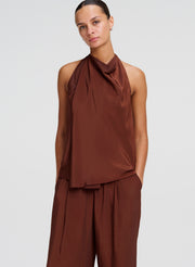 Woman wearing a brown sleeveless top and pants on a white background