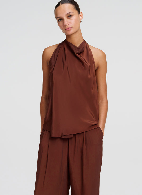 Woman wearing a brown sleeveless top and pants on a white background