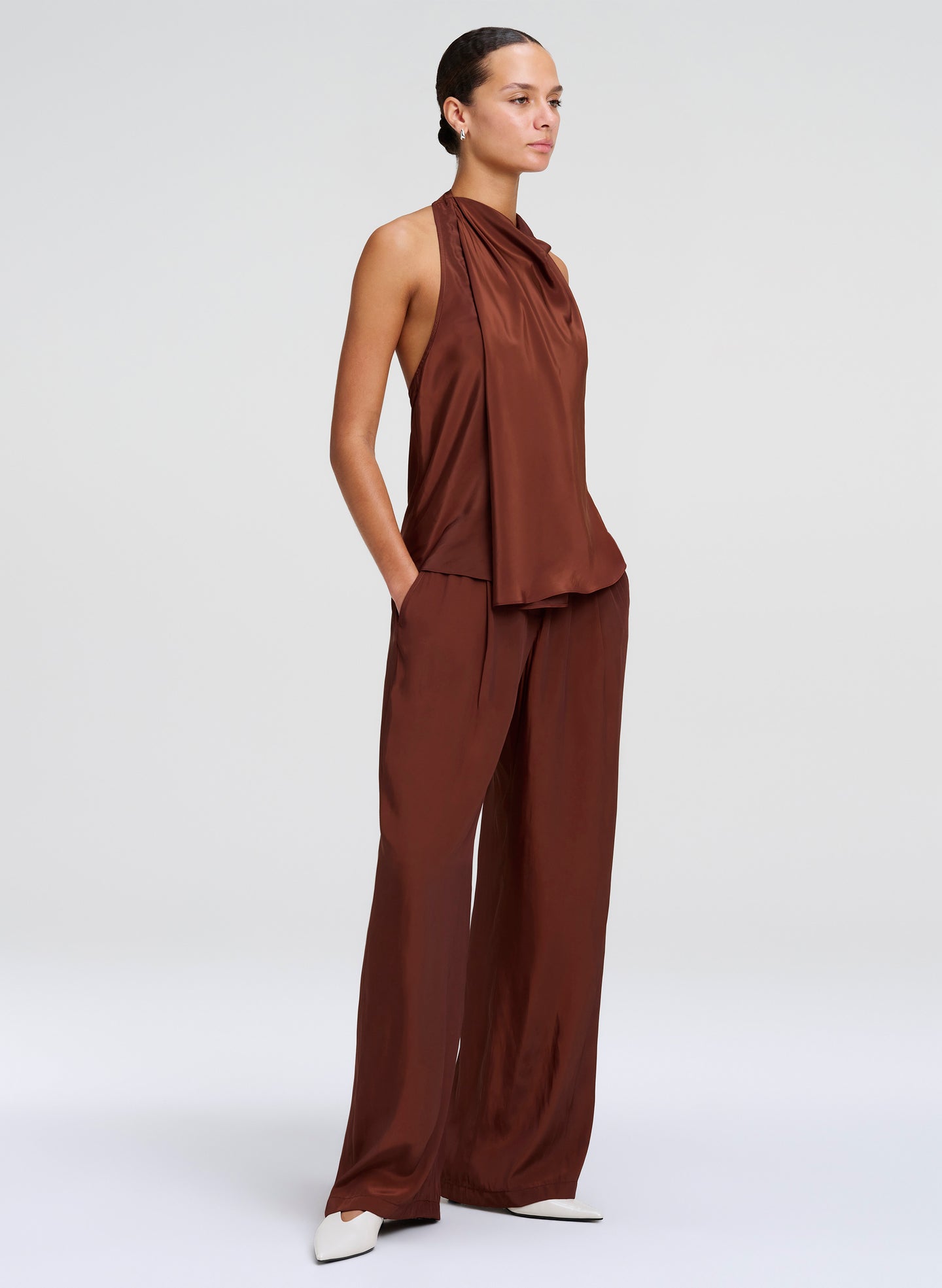 Woman wearing a brown sleeveless top and wide-leg pants on a white background