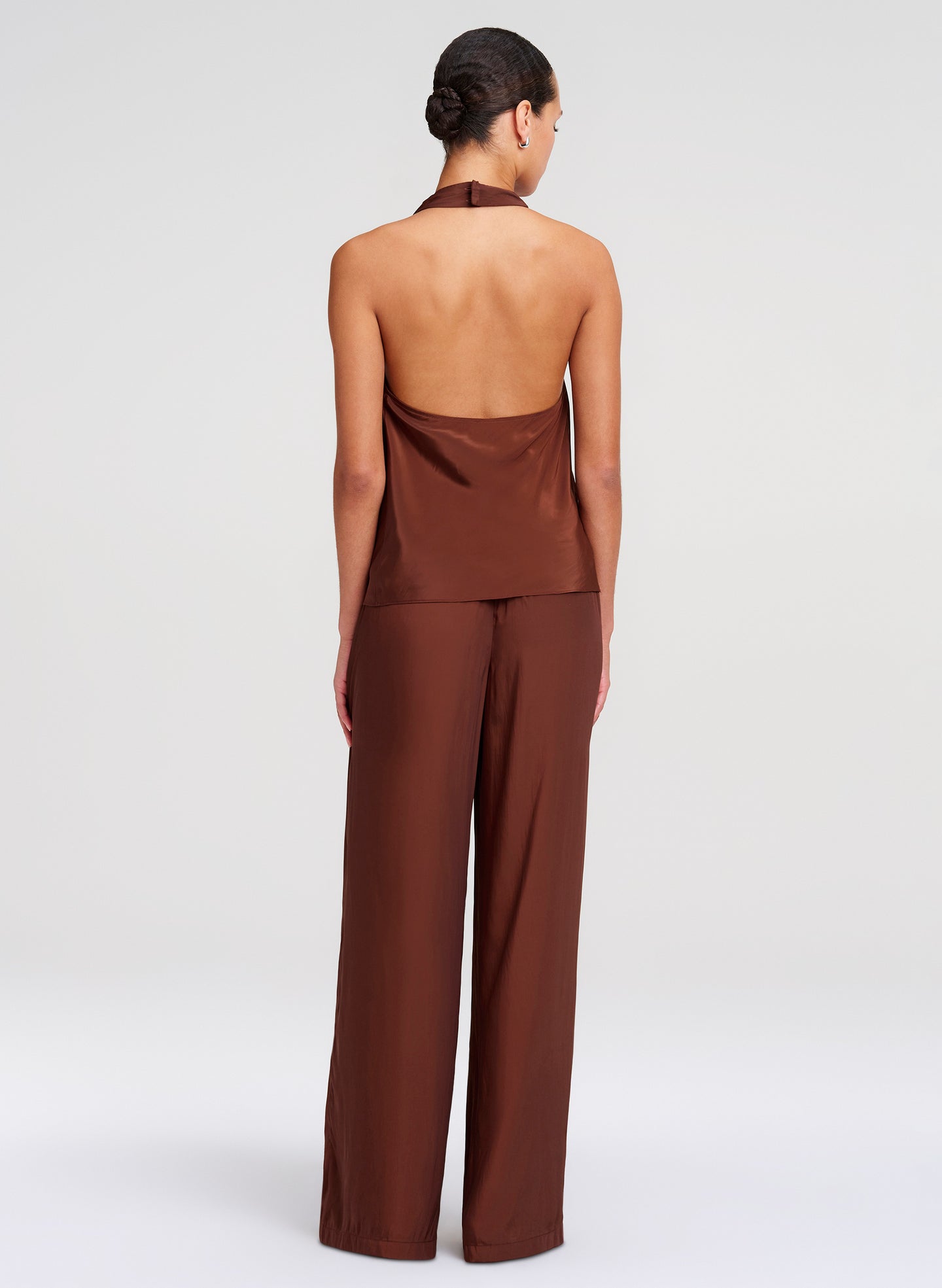 Woman wearing a brown halter top and wide-leg pants on a white background