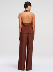 Woman wearing a brown halter top and wide-leg pants on a white background