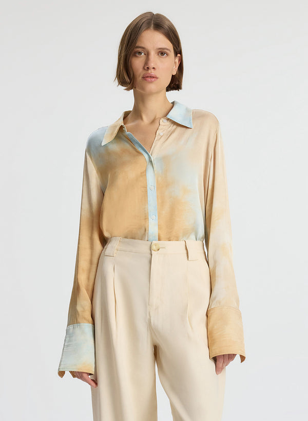 detail view of woman wearing long sleeve collared multicolored shirt and beige pants
