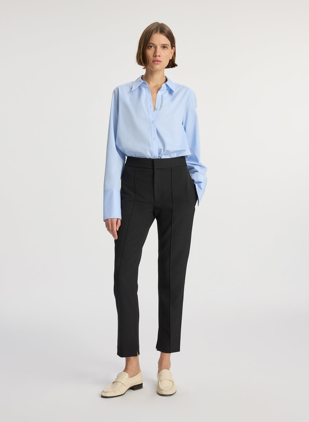 front view of woman wearing light blue button down collared shirt and black ankle length pants