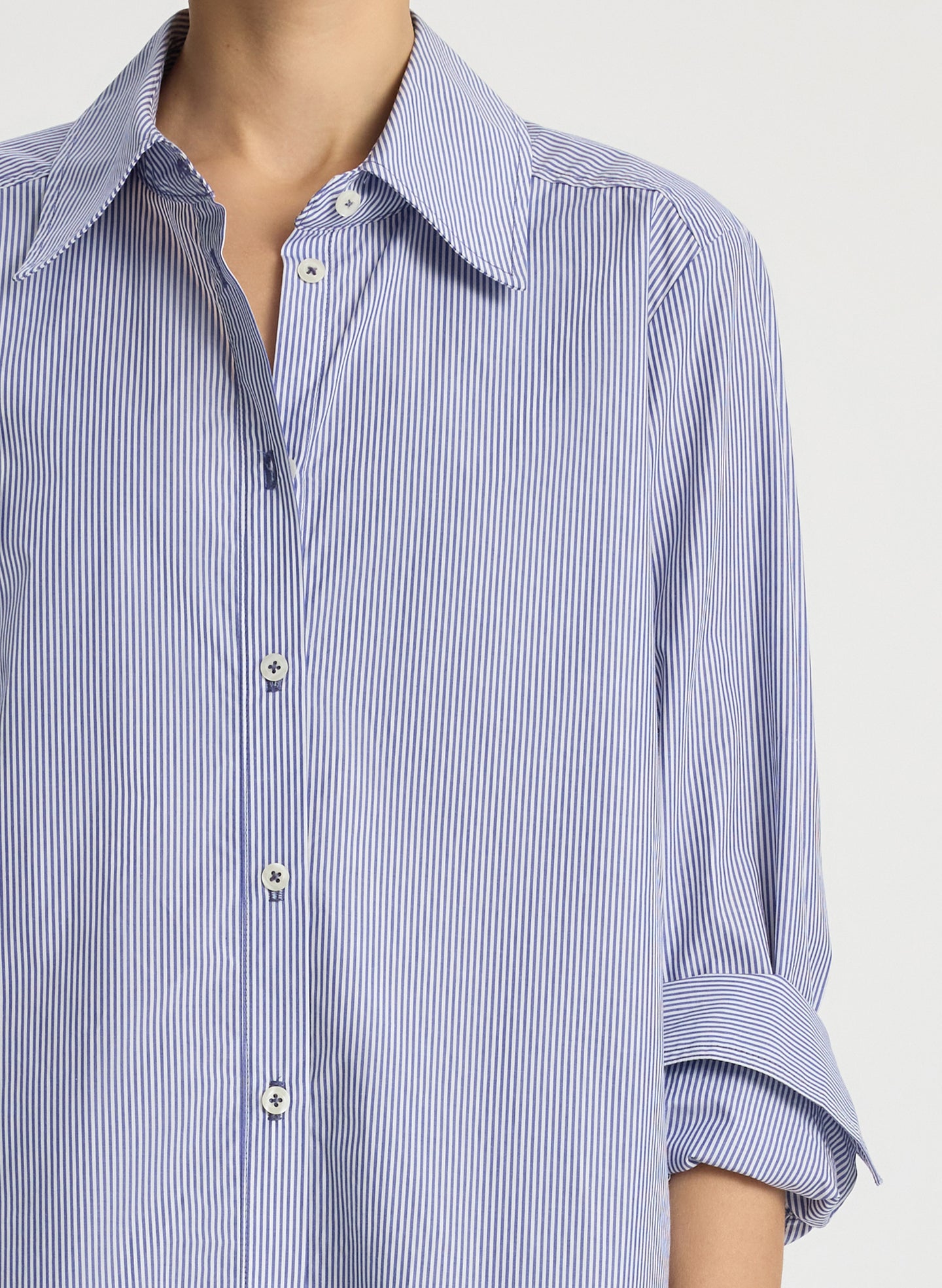 detail view of woman wearing blue striped button down collared shirt and navy blue pants