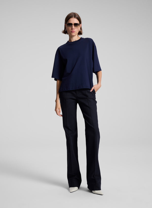 woman wearing goldtone aviator sunglasses, navy blue tee shirt and navy blue pants