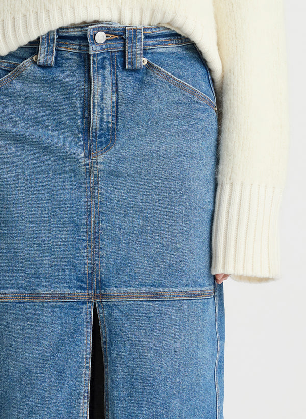 detail of front view of woman wearing ivory sweater and medium blue wash denim midi skirt