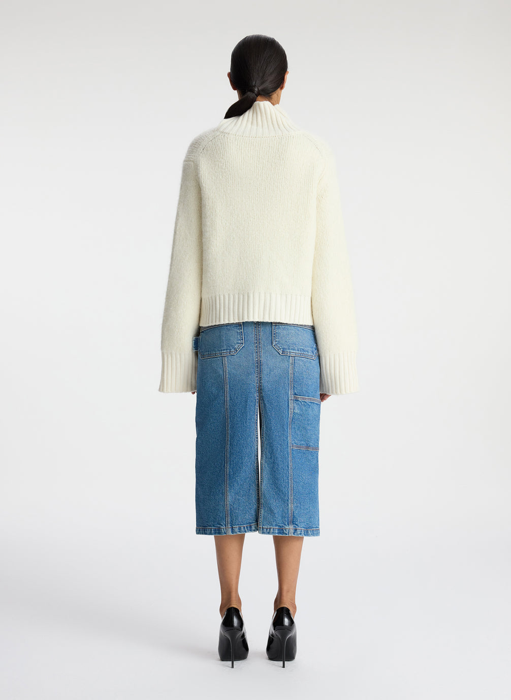 back view of woman wearing ivory sweater and medium blue wash denim midi skirt