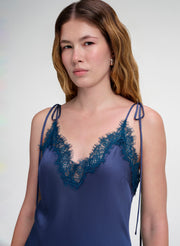 Woman wearing a blue lace-trimmed dress against a white background