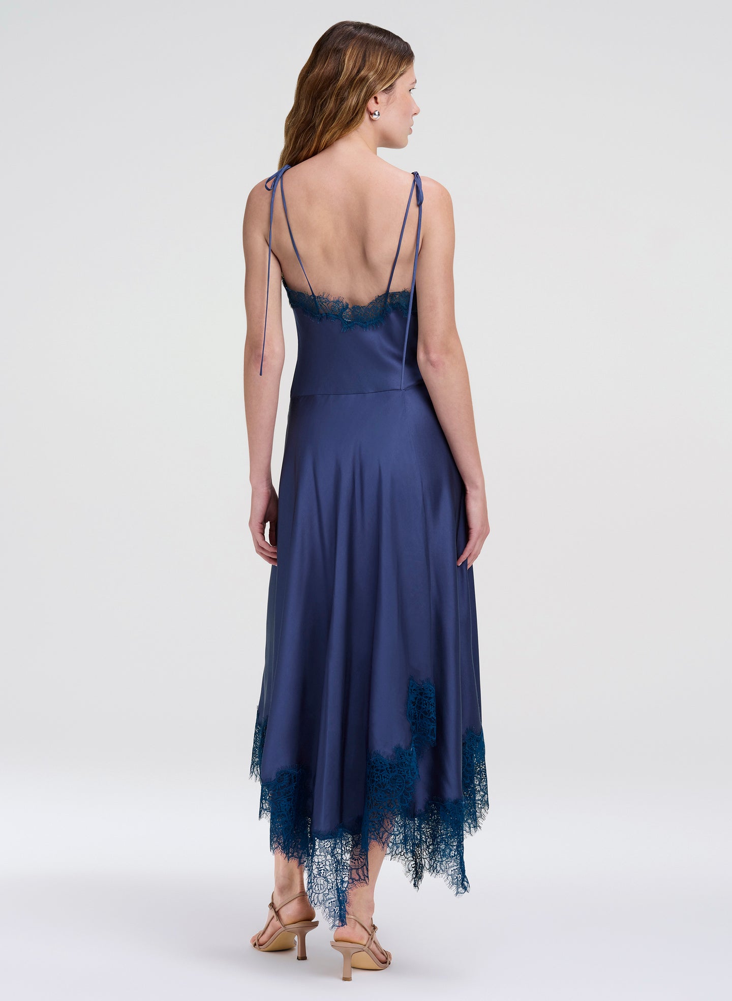 Woman wearing a navy blue dress with lace details on a white background