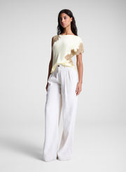 woman wearing butter yellow satin and lace top and cream wide leg pants