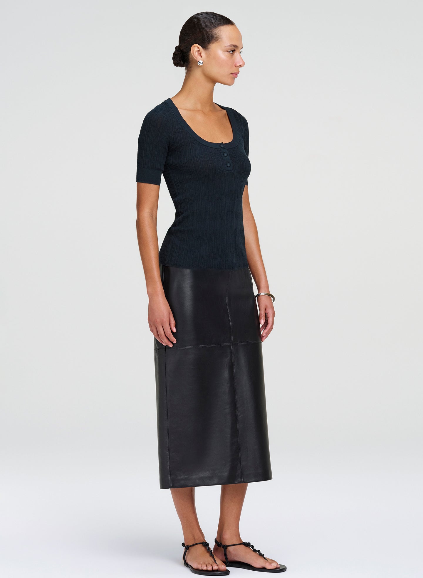 Woman wearing a dark green top and leather skirt on a white background
