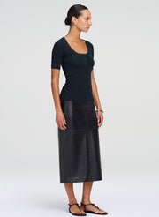 Woman wearing a dark green top and leather skirt on a white background