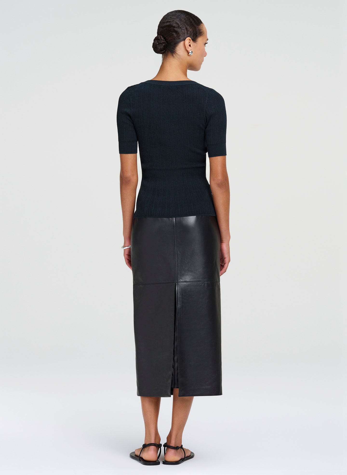 Woman wearing a green top and leather skirt on a white background