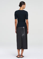 Woman wearing a green top and leather skirt on a white background