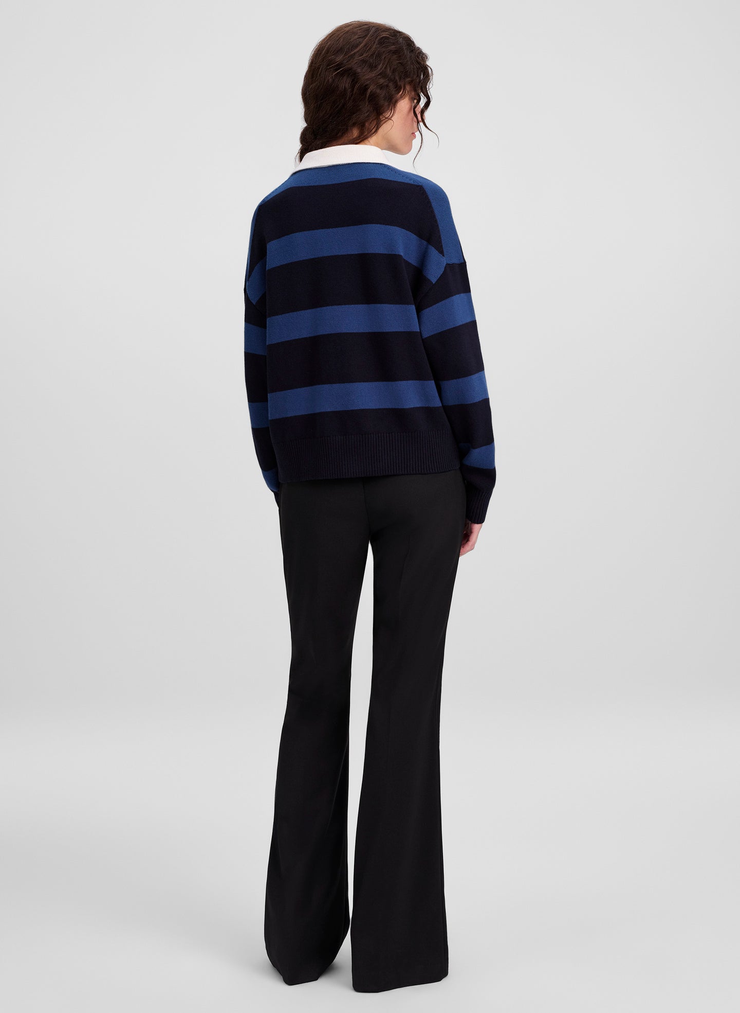 woman wearing striped sweater and black pants not facing camera
