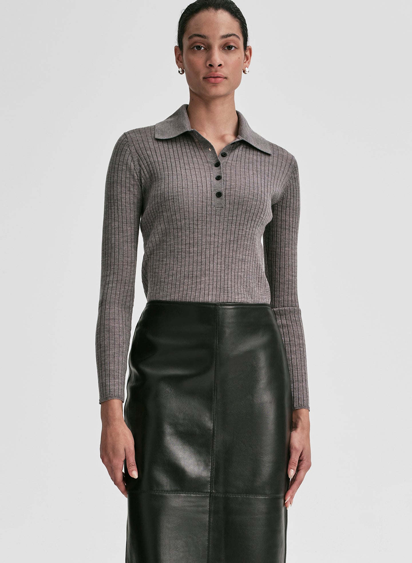 Woman wearing a gray shirt and black leather skirt on a light gray background