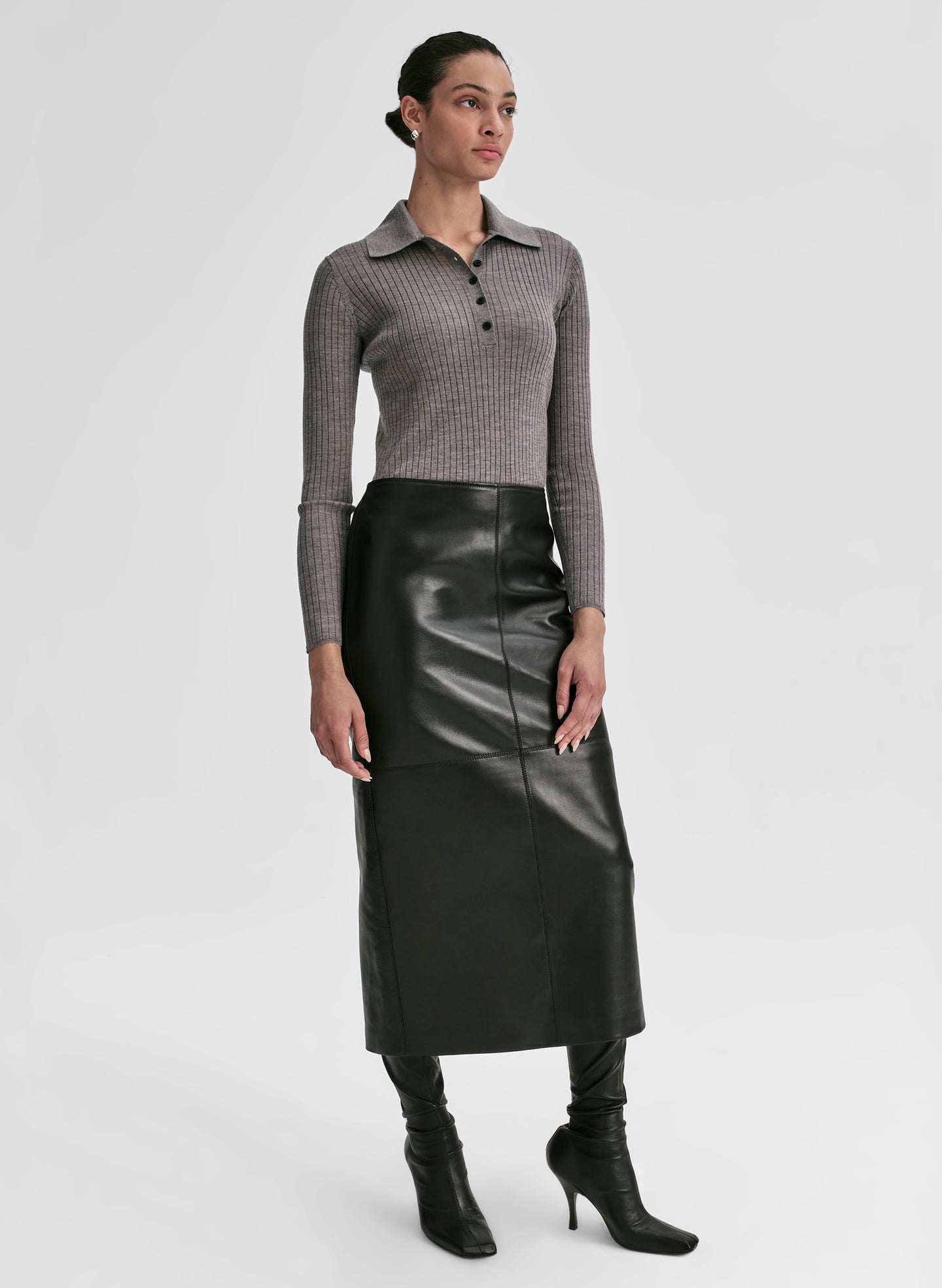 Woman wearing a gray shirt and black leather skirt on a light gray background