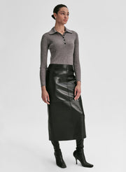 Woman wearing a gray shirt and black leather skirt on a light gray background