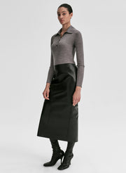 Woman wearing a gray shirt and black leather skirt on a light gray background