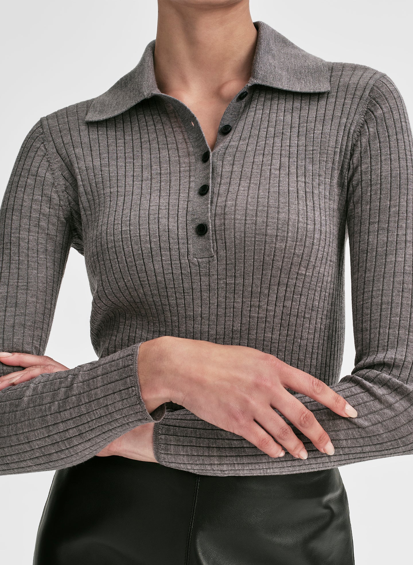 Woman wearing a gray shirt and black leather skirt on a light gray background