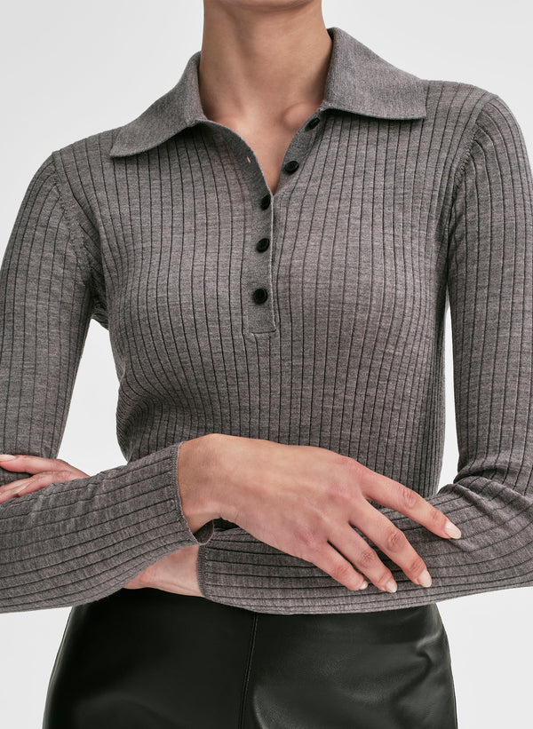 Woman wearing a gray shirt and black leather skirt on a light gray background