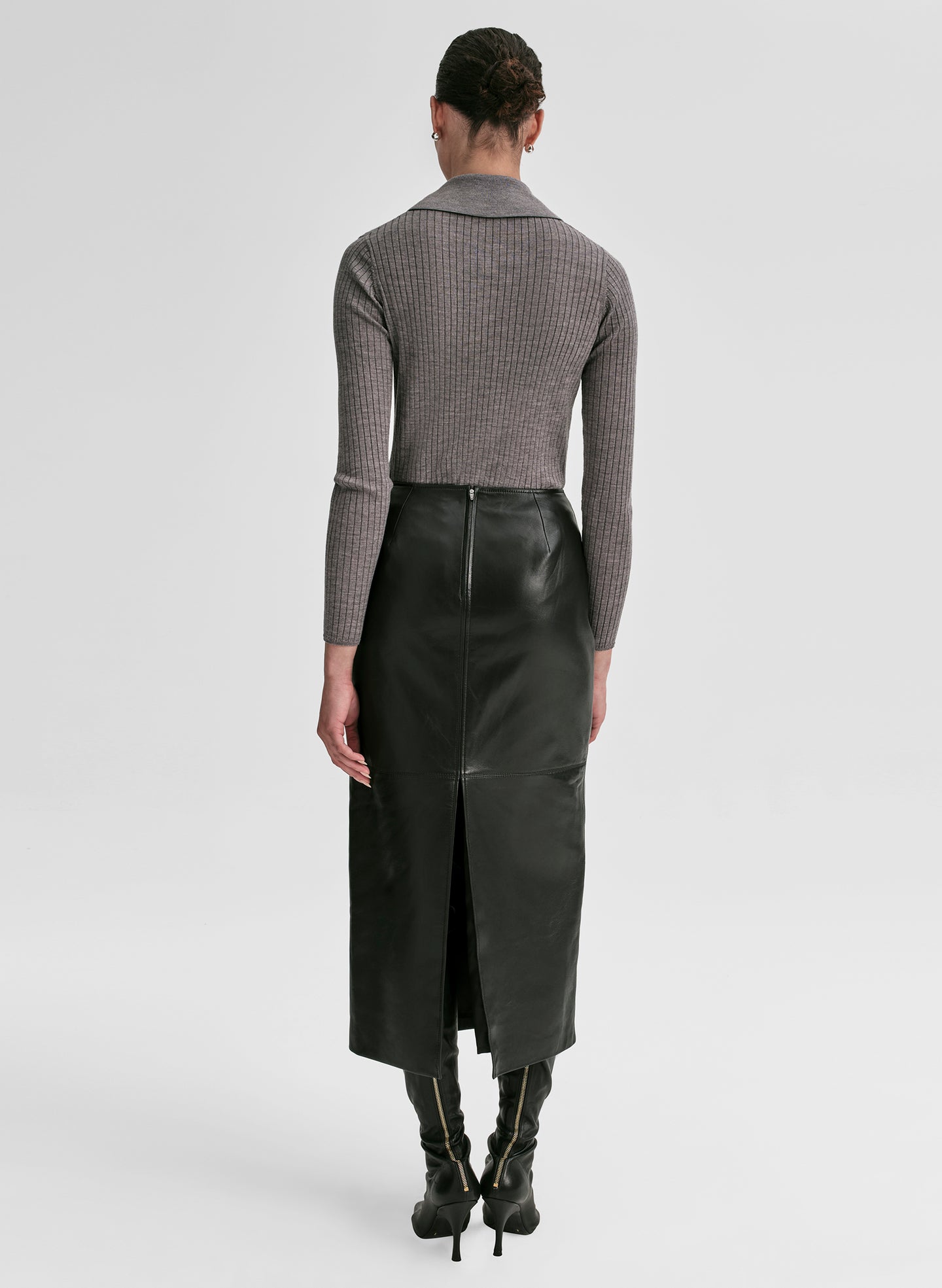 Woman wearing a gray shirt and black leather skirt on a light gray background