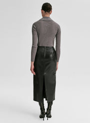 Woman wearing a gray shirt and black leather skirt on a light gray background