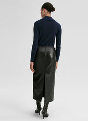 Woman wearing a navy ribbed long-sleeve shirt and black leather skirt on a light gray background