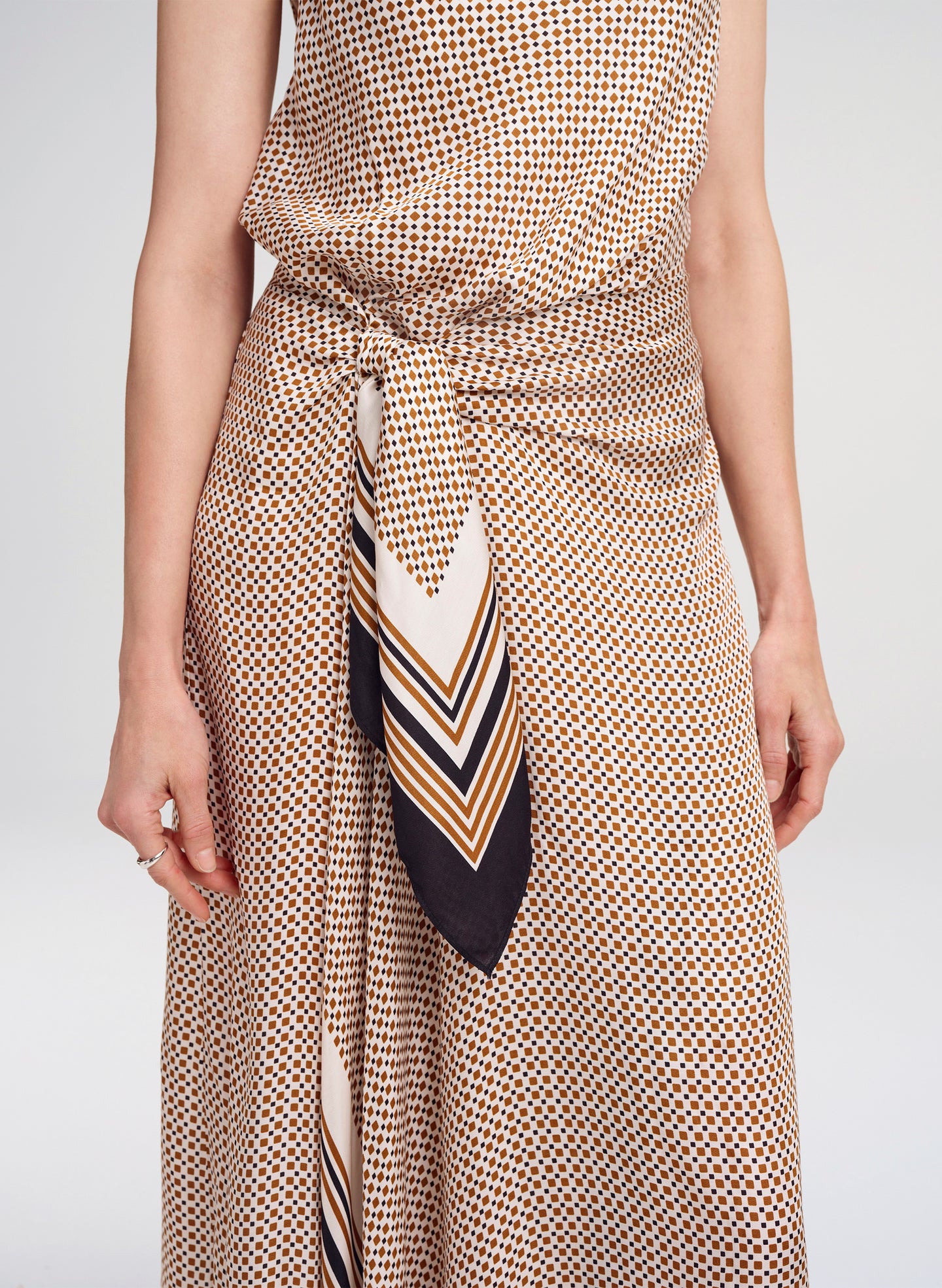 Person wearing a patterned dress with a matching scarf on a plain background