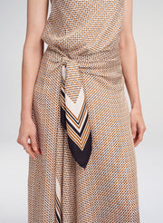 Person wearing a patterned dress with a matching scarf on a plain background
