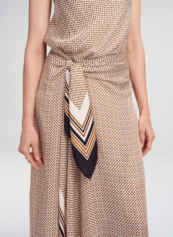 Person wearing a patterned dress with a matching scarf on a plain background