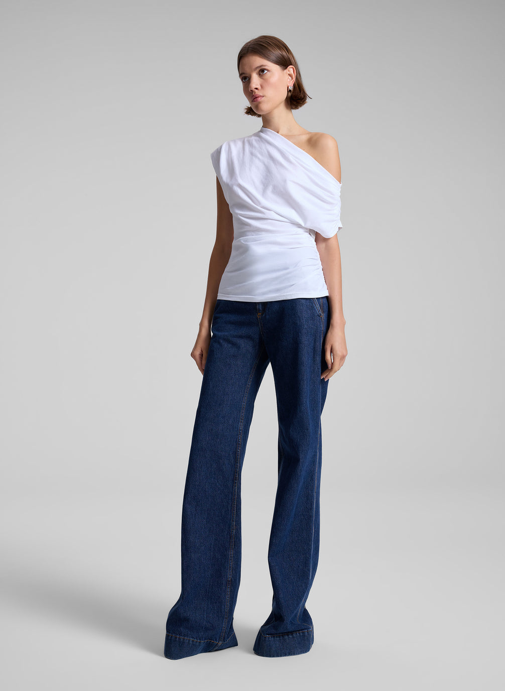 woman wearing white off the shoulder t shirt and medium wash denim