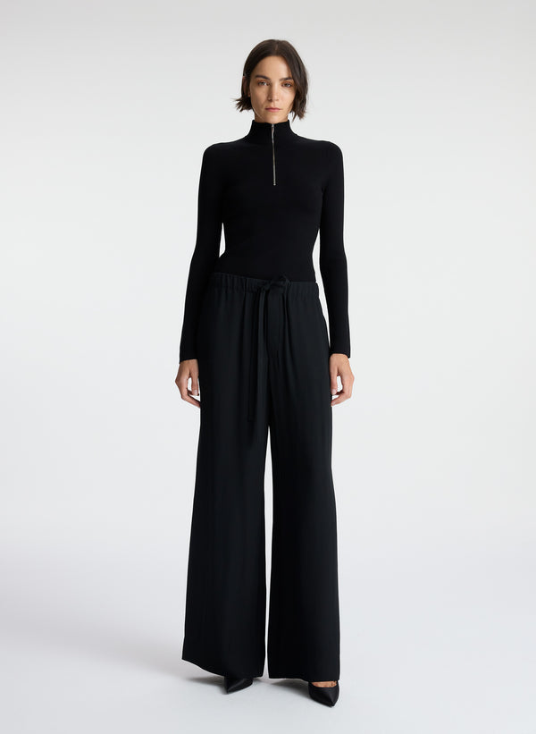 front view of woman wearing black knit top and black wide leg pants