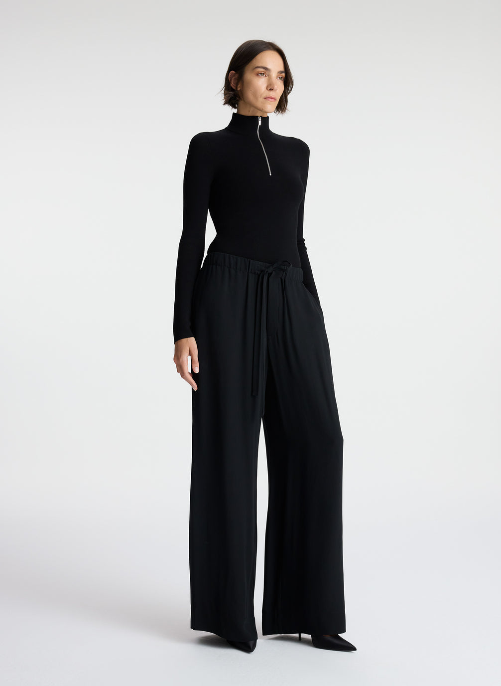 side view of woman wearing black knit top and black wide leg pants