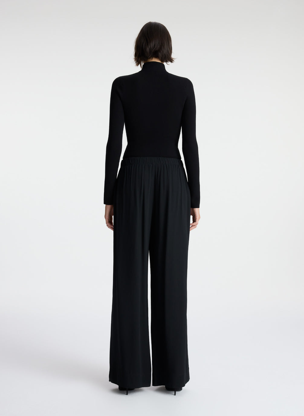 back view of woman wearing black knit top and black wide leg pants